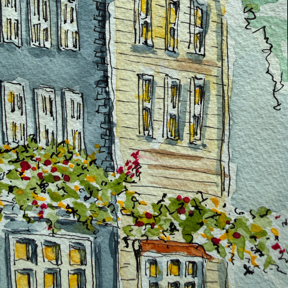 Detail of the yellow clapboard building and flowering vines beside the blue townhouse